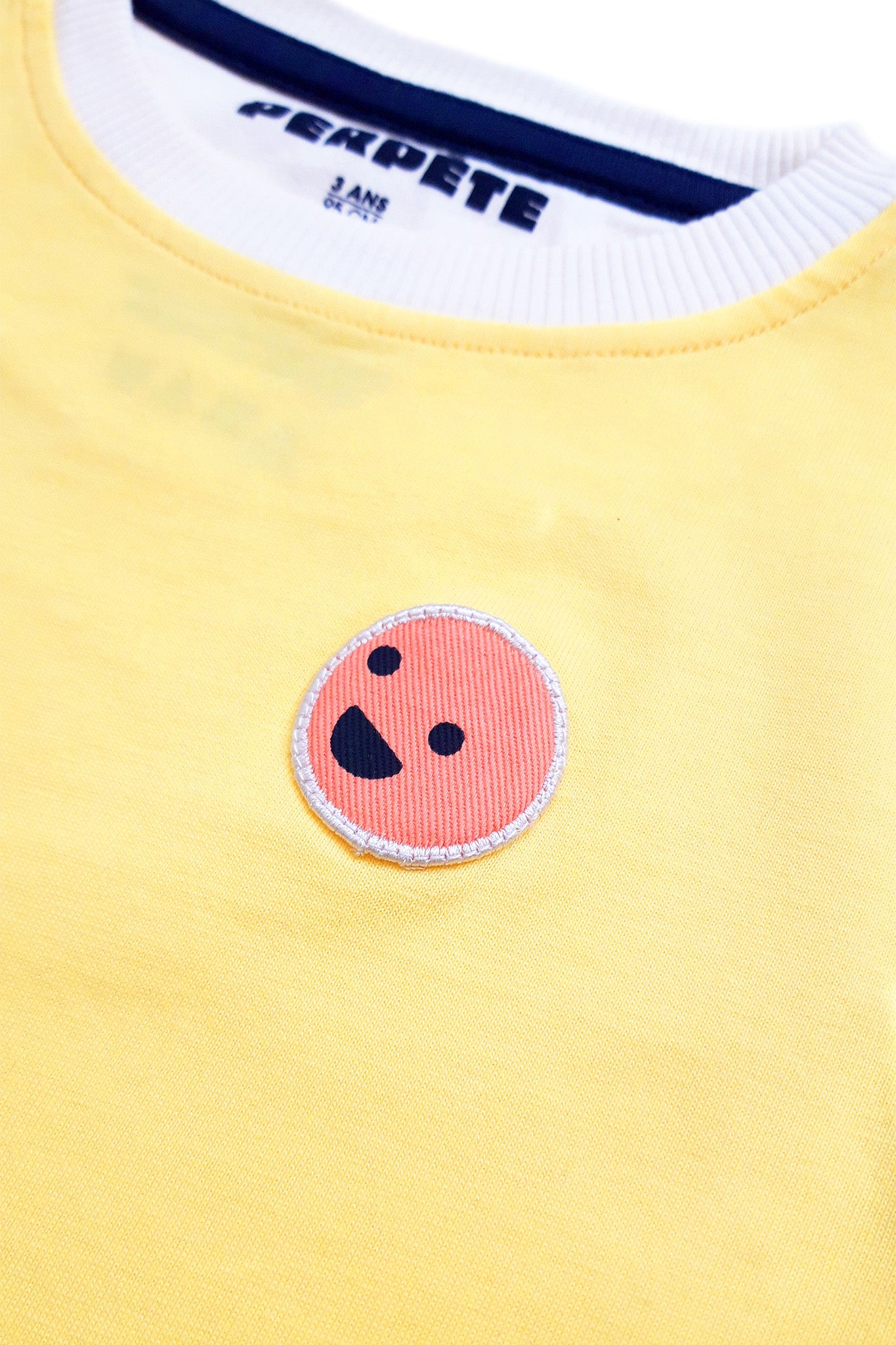 Zoom sur le patch du tee-shirt happy jaune citron.