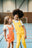 Robe Perpète Power enfant, en coton bio, coloris corail, bretelles réglables par boutons, portée par Emmie, vue de face