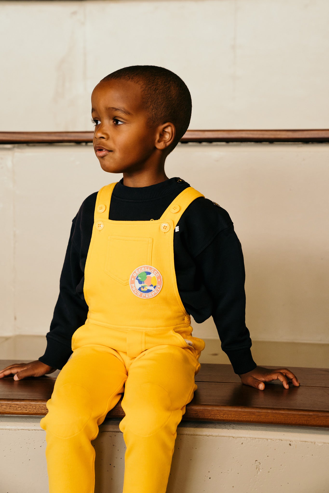 Salopette enfant Shiny Perpète, en coton bio, mixte, coloris jaune, portée par Luckas, vue de face