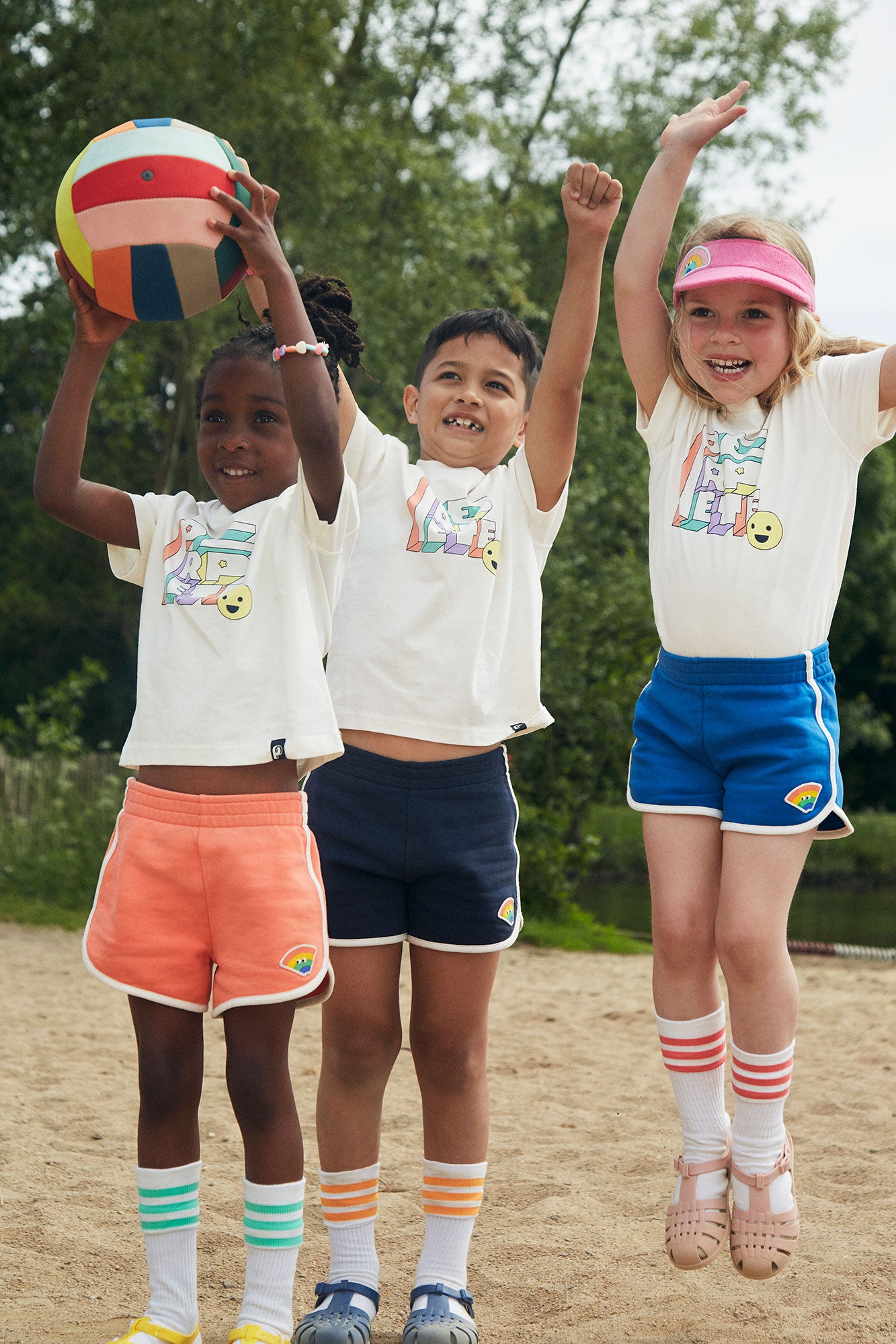 Trois enfants portent le short simply en différentes couleurs, ils jouent sur la plage.