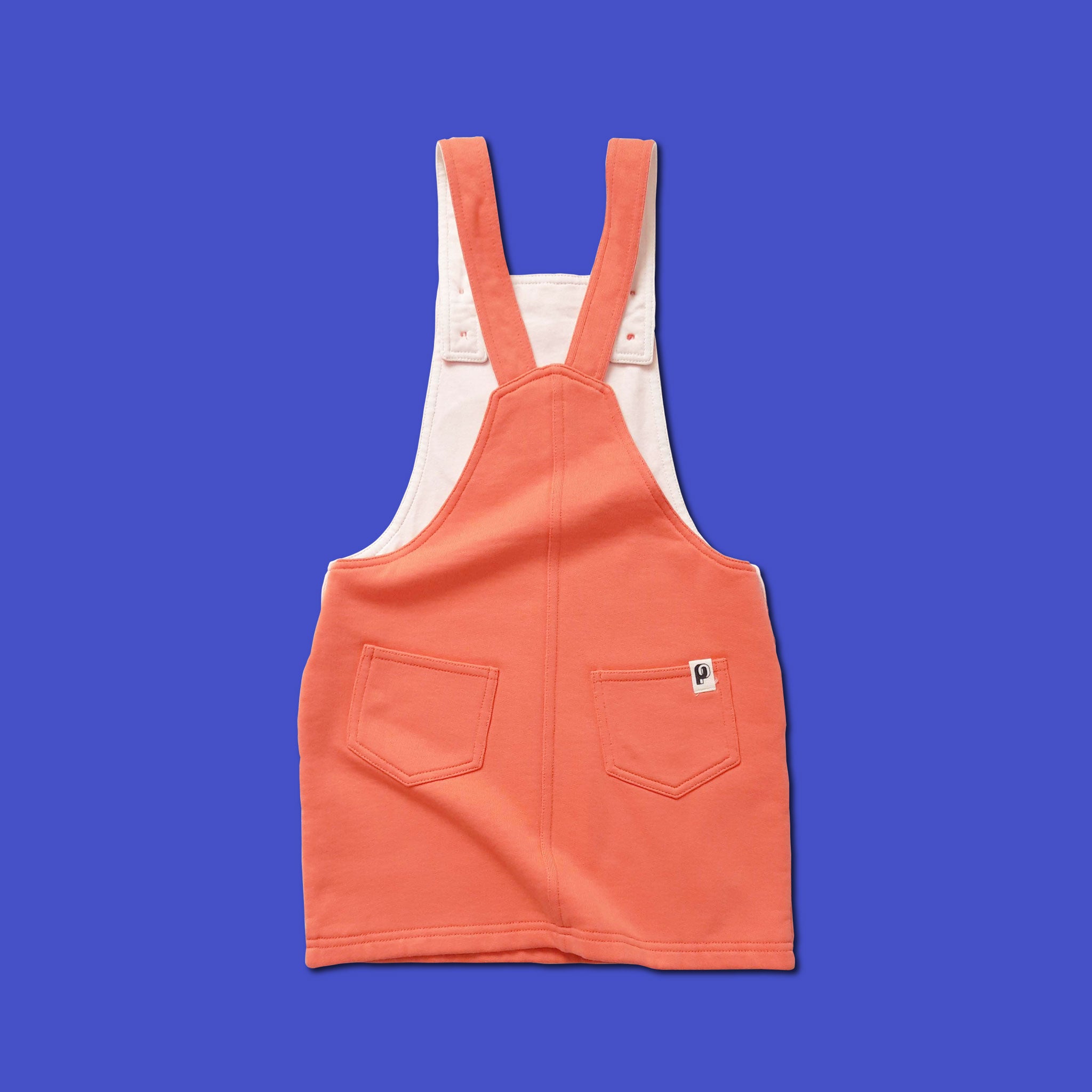 Robe Perpète Power enfant, en coton bio, coloris corail avec patch imprimé sur la poitrine, à plat, avec  bretelles reglables par boutons, vue de dos